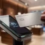 Hand tapping a metal credit card on a contactless payment terminal in a high-end store