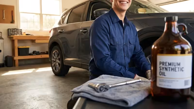 Smiling man in a blue shirt prepares for an oil change in his garage.